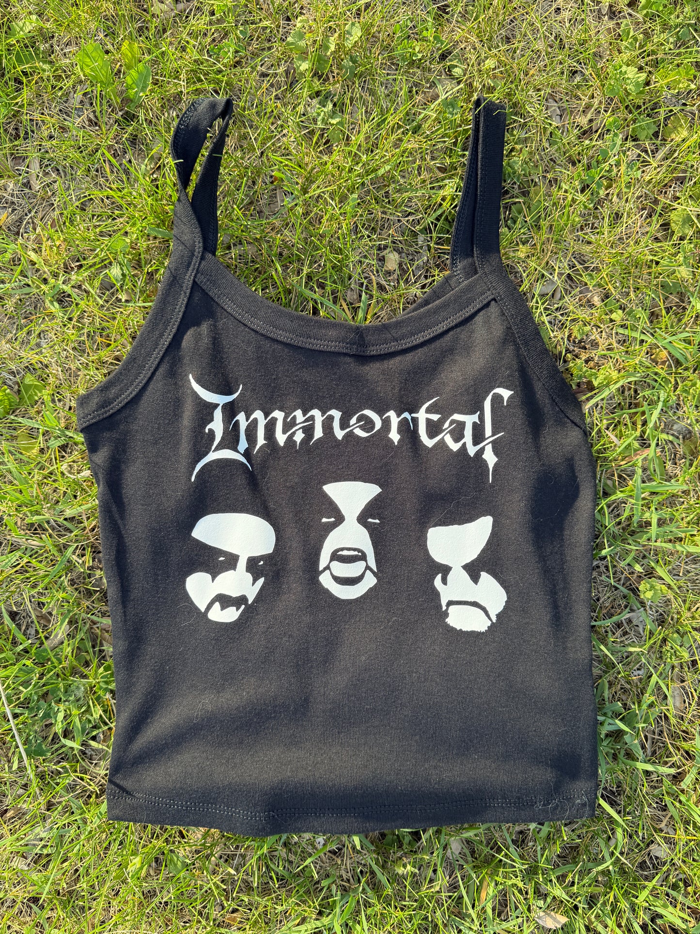 A black crop top with white text printed on it, lying on the grass.