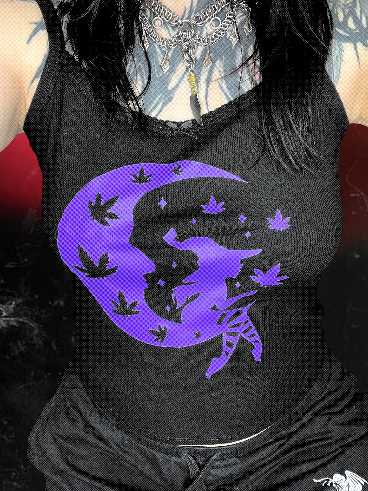 a person wearing a black tank top with a purple design featuring a moon and leaves.