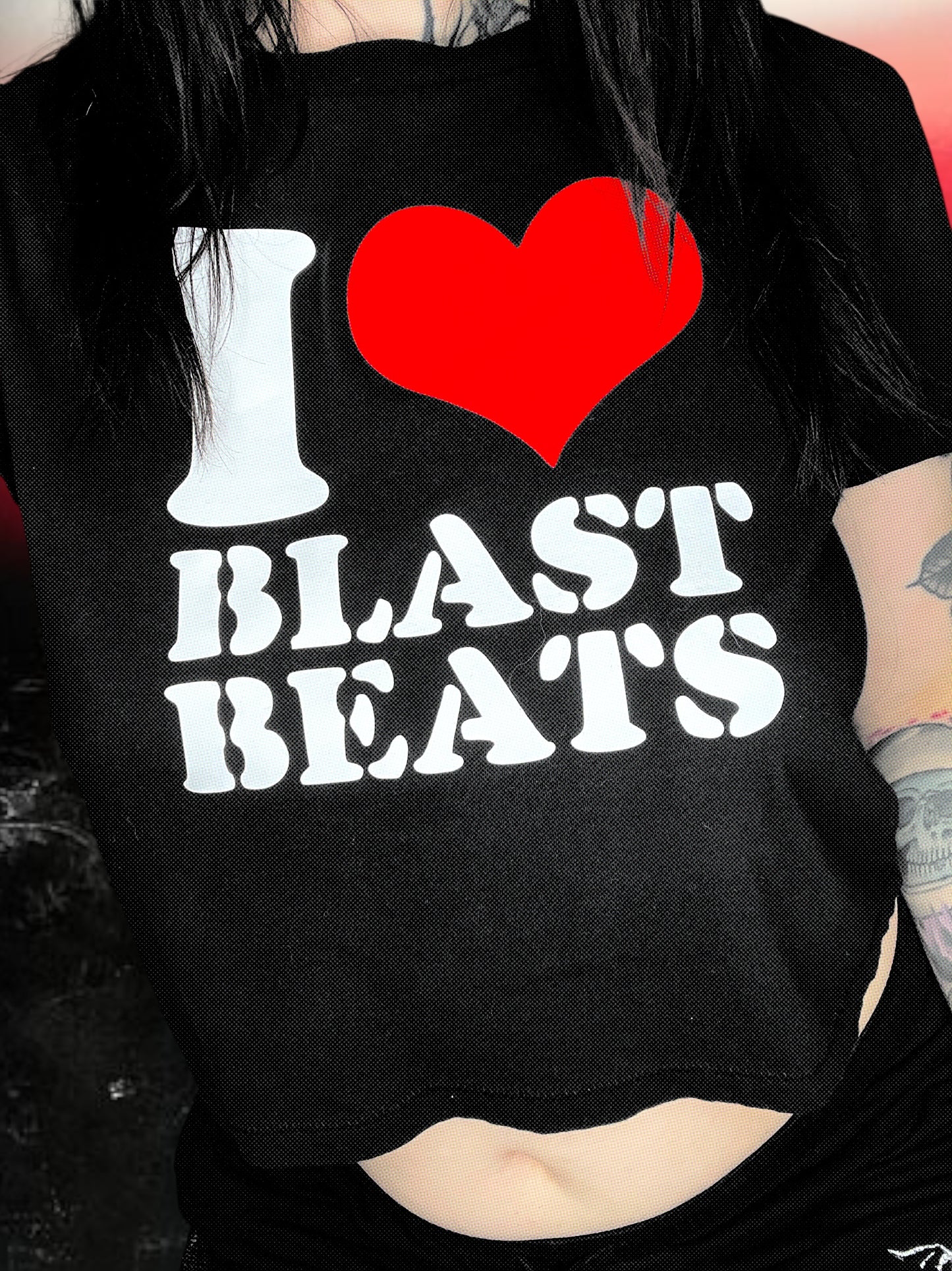 Black cropped t-shirt with a retro-style print that says “I ❤️ BLAST BEATS” in white text and a large red heart. The shirt is laid flat over a sparkly black-and-white cosmic background.