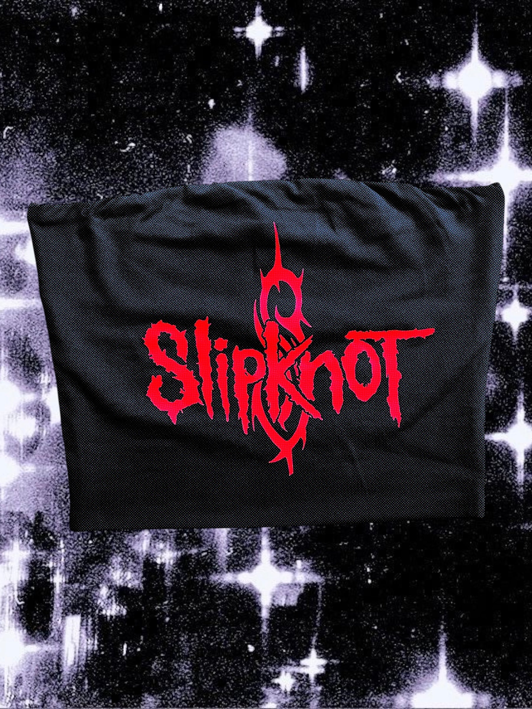 Black tube top featuring a bright red Slipknot logo with the band’s signature tribal “S” symbol in the background. The top is laid flat on a sparkly black-and-white star field backdrop.