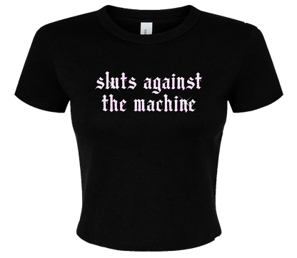 A black t-shirt with the text "sluts against the machine" printed on it in a stylized font.