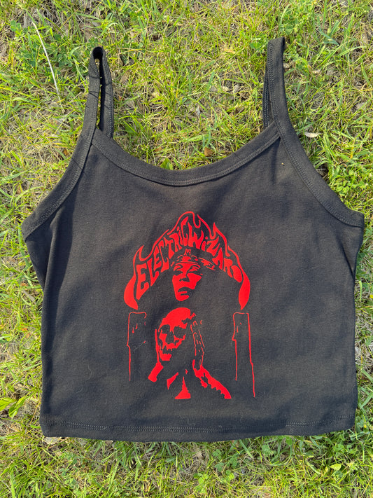 a black crop top with a red graphic design on it, lying on a grassy surface.