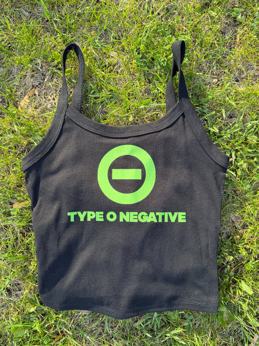 A black tank top with a green logo and text printed on it, lying on a grassy surface.