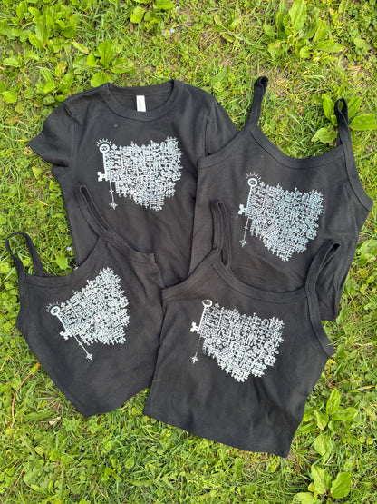 a collection of black t-shirts and tank tops lying on a grassy surface.