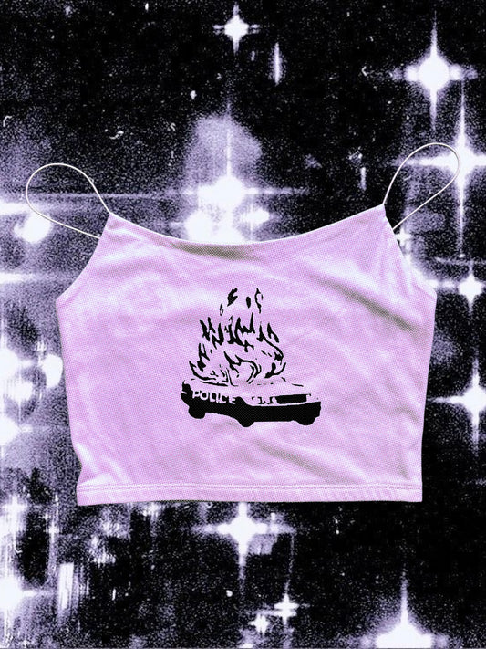 Light pink spaghetti strap cami with a black graphic of a burning police car. The word “POLICE” is visible on the side of the car, which is engulfed in stylized flames. The shirt is laid flat on a black-and-white cosmic starry background.