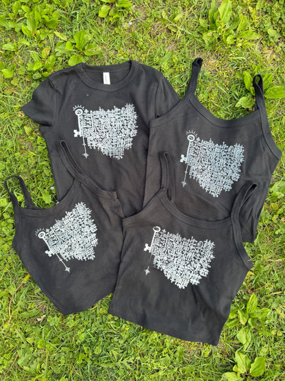 a collection of black t-shirts and tank tops lying on a grassy surface.