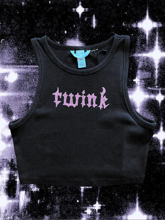 Black ribbed cropped tank top with pink glitter gothic text that reads “twink” across the chest. Shirt is laid flat against a black-and-white cosmic starry background.