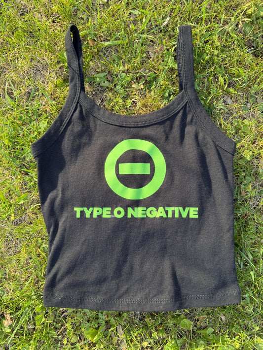 a black crop top with a green logo on it, lying on a grassy surface.