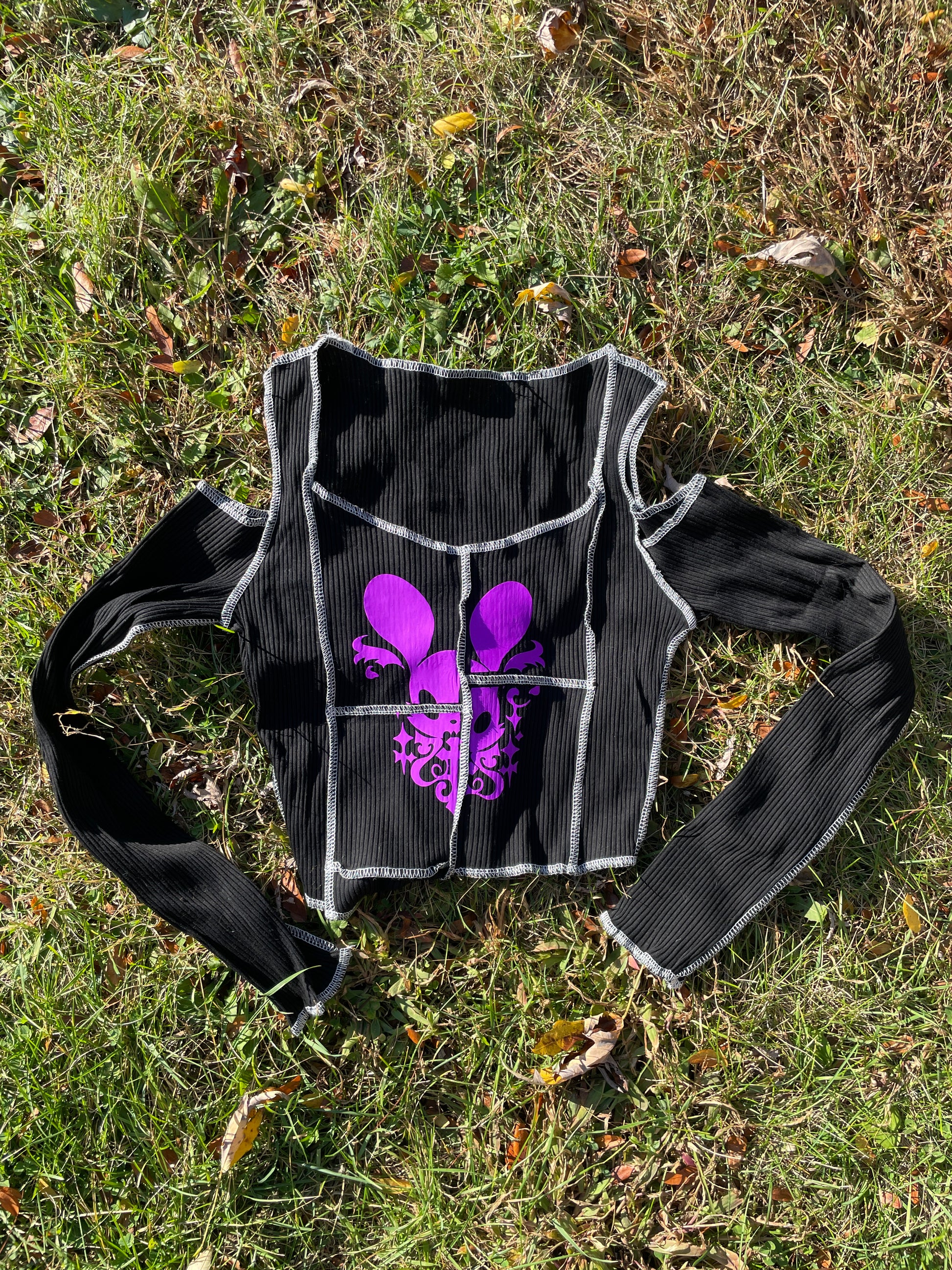 a black and purple shirt laying on top of a grass covered field